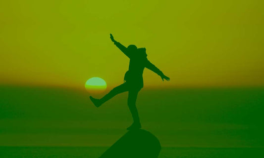 How is Good Academic Records important? - chikara houses - man on a rock with the red sunset in the background hitting the sun like a if it was a footlball ball