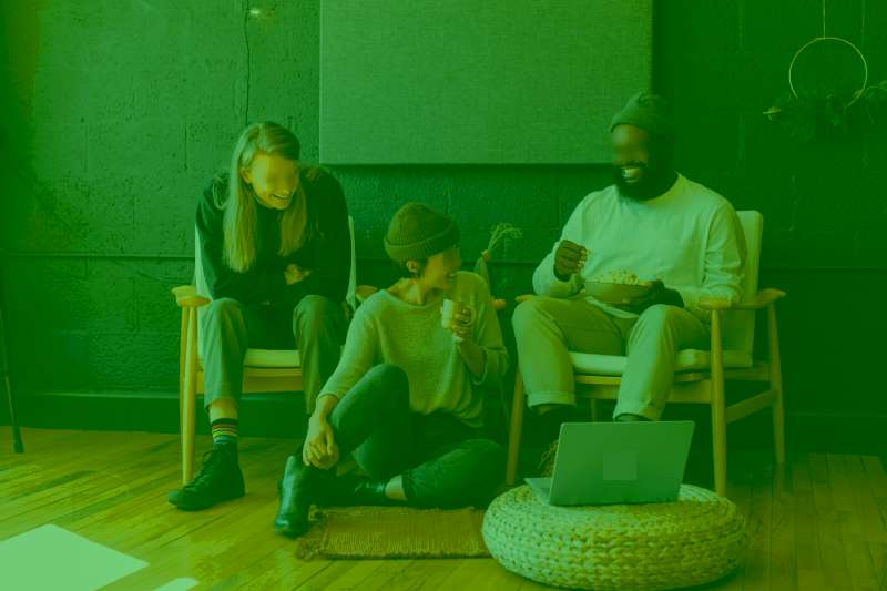 Chikara Houses CoLiving Concept Shared Home - People enjoying seated on chairs, sofa and floor with a laptop on a pillow sharing home good vibe and sobriety of design